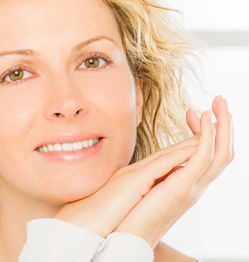 Woman with clear skin touching her face against a white background