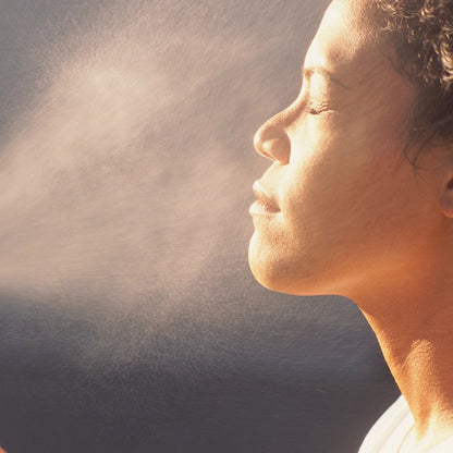 Woman mist her face with rose distillate