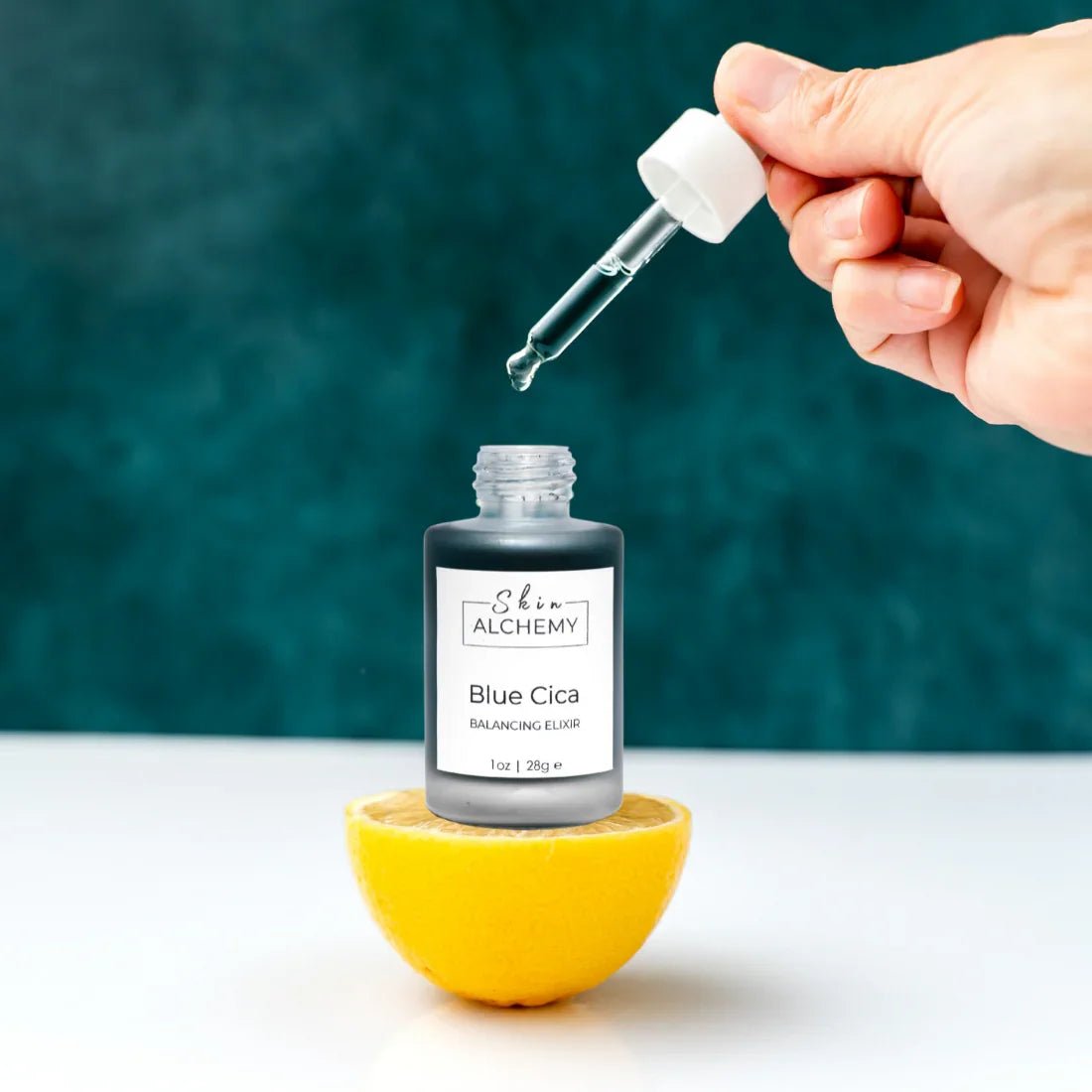 A hand holding the dropper to a face oil bottle