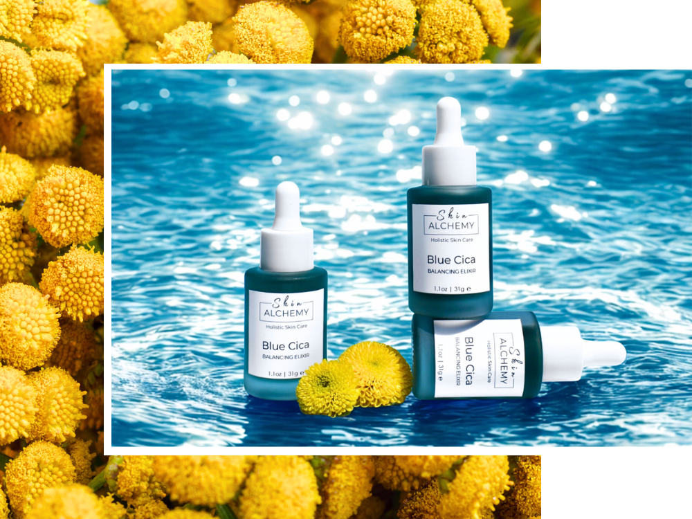 Three Alchimist Blue Cicil skincare bottles on a blue water background with yellow flowers.