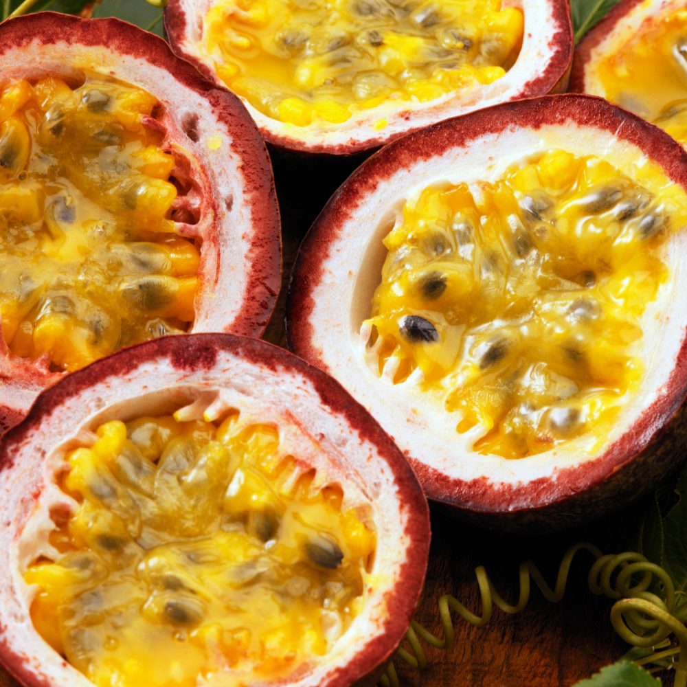 Halved passion fruits with yellow flesh and red outer skin on a wooden surface.